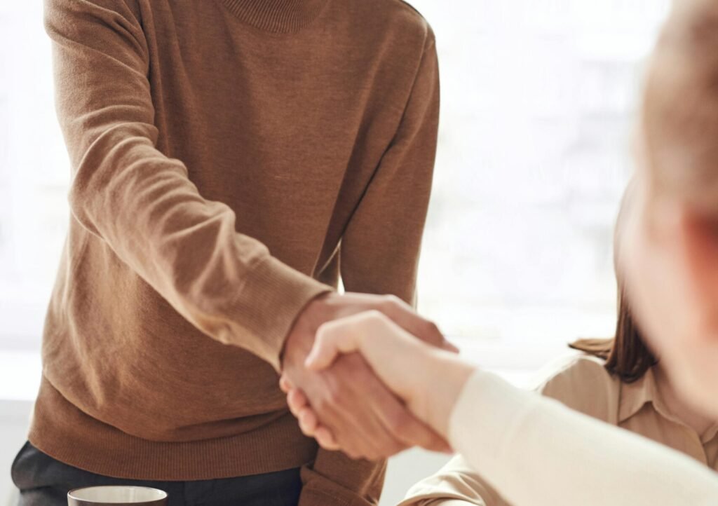 Smiling professionals engage in a welcoming handshake at a business meeting indoors.